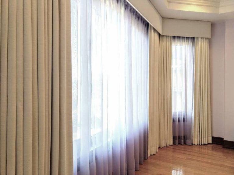 Sheers and blackout curtains under a cream color cornice