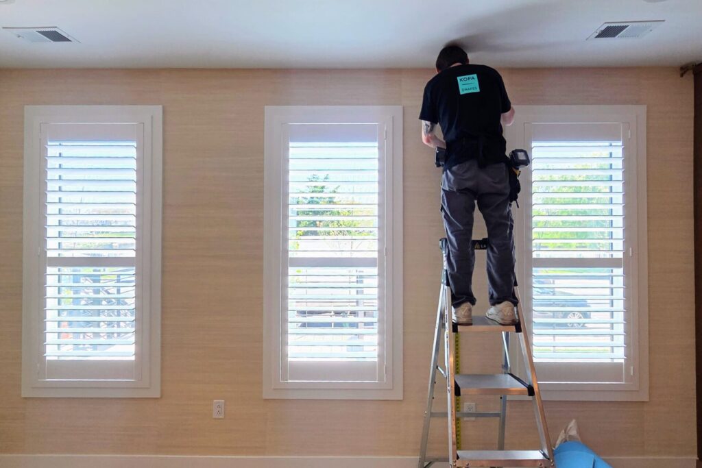 Asbury Park Custom Drapes Installation, curtains in a light sand color with installer on a ladder